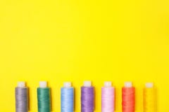 Handicraft background. Set of multicolored spools of thread on yellow background with copy space. Accessories for needlework royalty free stock photo Handicraft background. Set of multicolored spools of thread on yellow background with copy space. Accessories for needlework royalty free stock photo