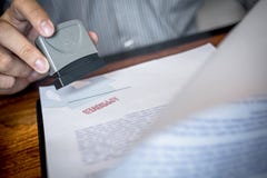 Hands of businessman stamp on paper document to approve business investment contract agreement stock photography Hands of businessman stamp on paper document to approve business investment contract agreement stock photography