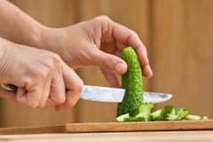 Hands cutting cucumber for salad on the wooden chopping board Royalty Free Stock Image Hands cutting cucumber for salad on the wooden chopping board Royalty Free Stock Image