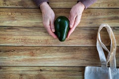 Hands of an old woman holding fresh organic avocado. Eco Shopping Bag on wooden background, Flat Lay royalty free stock image Hands of an old woman holding fresh organic avocado. Eco Shopping Bag on wooden background, Flat Lay royalty free stock image