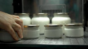 Hands putting jars with milk into cold store.