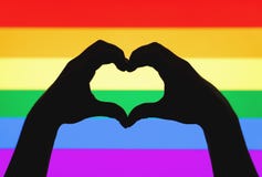 Hands showing heart sign on gay pride and LGBT rainbow flag
