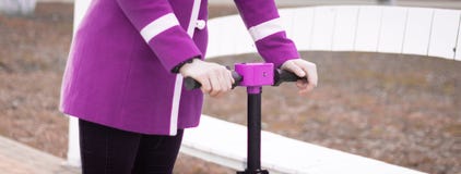 Hands of a young woman holding the steering wheel of an electric scooter. Visible pink - purple coat. No face. Panorama royalty free stock photography Hands of a young woman holding the steering wheel of an electric scooter. Visible pink - purple coat. No face. Panorama royalty free stock photography