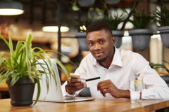 African man sending money with smart phone and laptop. royalty free stock photo African man sending money with smart phone and laptop. royalty free stock photo