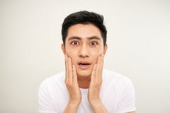 Handsome Asian man is touching his face and smiling while looking into the mirror stock image Handsome Asian man is touching his face and smiling while looking into the mirror stock image