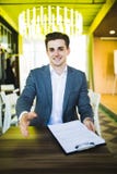 Handsome buisnessman with open hand ready for handshake before sign of contract at his workplace in office royalty free stock images Handsome buisnessman with open hand ready for handshake before sign of contract at his workplace in office royalty free stock images