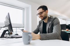 Handsome businessman is using a smartphone and smiling while working in office royalty free stock image Handsome businessman is using a smartphone and smiling while working in office royalty free stock image