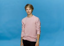 Happy blonde teenager smiling and posing in pink blouse against blue background royalty free stock images Happy blonde teenager smiling and posing in pink blouse against blue background royalty free stock images