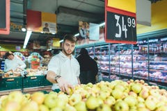 A handsome man chooses apples in a supermarket. The family man buys fruit in the store. Shopping in a supermarket. stock photos A handsome man chooses apples in a supermarket. The family man buys fruit in the store. Shopping in a supermarket. stock photos