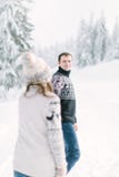 Handsome man holding hand of his lovely bride walking on the snow in a magic winter forest stock images Handsome man holding hand of his lovely bride walking on the snow in a magic winter forest stock images
