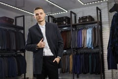 Handsome man stands in suit shop fashionable rich male dressed in expensive clothes posing indoors royalty free stock photos Handsome man stands in suit shop fashionable rich male dressed in expensive clothes posing indoors royalty free stock photos