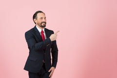 Middle age male in suit and red tie pointing away side with his finger on pink rose background stock photography Middle age male in suit and red tie pointing away side with his finger on pink rose background stock photography