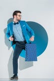 handsome stylish young man with shopping bag looking away while stepping through hole royalty free stock photography handsome stylish young man with shopping bag looking away while stepping through hole royalty free stock photography