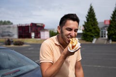 Handsome young brunette man eating hot dog. royalty free stock images Handsome young brunette man eating hot dog. royalty free stock images