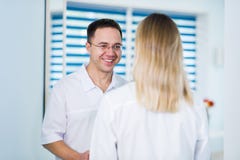 Handsome young doctor is talking with his beautiful female assistant, standing in waiting room of the clinic stock photos Handsome young doctor is talking with his beautiful female assistant, standing in waiting room of the clinic stock photos
