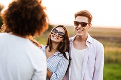 Handsome young man and beautiful young woman are standing in the field with friends and laughing. stock image Handsome young man and beautiful young woman are standing in the field with friends and laughing. stock image