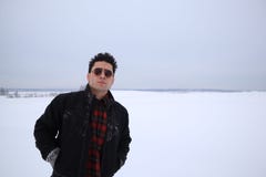 Handsome young man in sunglasses stands in a field in winter. stands on a hill and looks into the distance. the majestic sky in th stock images Handsome young man in sunglasses stands in a field in winter. stands on a hill and looks into the distance. the majestic sky in th stock images