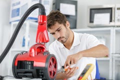 Handsome young repairman fixing vacuum cleaner stock photography Handsome young repairman fixing vacuum cleaner stock photography