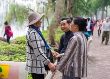 Hanoi Vietnam - Mars 15, 2015: Ett par som ser lyckligt deras vän på Hoan Kiem sjön, Hoan Kiem område Kvinnorna som rymmer händer arkivbilder Hanoi Vietnam - Mars 15, 2015: Ett par som ser lyckligt deras vän på Hoan Kiem sjön, Hoan Kiem område Kvinnorna som rymmer händer arkivbilder