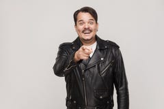The happiness man, wearing black jacket, having happiness looks. Pointing finger at camera and toothy smiling. Isolated studio shot on gray background Stock Image The happiness man, wearing black jacket, having happiness looks. Pointing finger at camera and toothy smiling. Isolated studio shot on gray background Stock Image