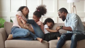 Happy african american family with kids laugh tickle at home