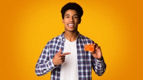 Happy African-american Guy Holding Credit Card And Point On It Royalty Free Stock Image