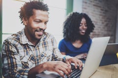 Happy African couple having rest at a home: black man sitting at the table,using laptop and laughing,looking through Royalty Free Stock Photography Happy African couple having rest at a home: black man sitting at the table,using laptop and laughing,looking through Royalty Free Stock Photography