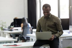 Happy afro american businessman sitting on his desk and typing royalty free stock image Happy afro american businessman sitting on his desk and typing royalty free stock image