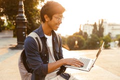 Happy asian male student in eyeglasses using laptop computer stock photos Happy asian male student in eyeglasses using laptop computer stock photos