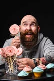 Happy bearded bald man holding two cream cakes on black background. royalty free stock image Happy bearded bald man holding two cream cakes on black background. royalty free stock image