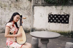 Happy Beautiful Asian Chinese Woman Artist In Traditional Chi-pao Cheongsam In A Garden Play Musical Instruments Pipa Chinese Lute Royalty Free Stock Image