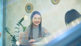 Happy beautiful girl sits in a cafe with her girlfriends. Tell a story during this. Enjoying time together while stock footage Happy beautiful girl sits in a cafe with her girlfriends. Tell a story during this. Enjoying time together while stock footage