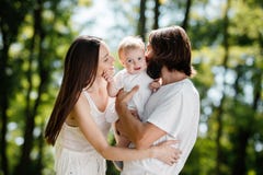 Happy beautiful parents dressed in the white casual clothes spending sunny day in the park with there little daughter. stock photos Happy beautiful parents dressed in the white casual clothes spending sunny day in the park with there little daughter. stock photos