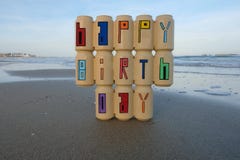 Happy Birthday text with recycled and painted beer cans on the beach