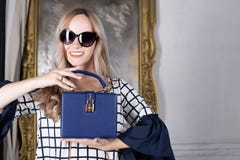 Happy blonde woman in sunglasses holding blue leather purse. Spa royalty free stock images Happy blonde woman in sunglasses holding blue leather purse. Spa royalty free stock images