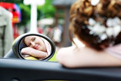 Happy bride looks in mirror of car at wedding walk royalty free stock photo Happy bride looks in mirror of car at wedding walk royalty free stock photo