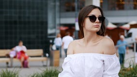 Happy businesswoman rest on bench on crowded city street, wearing sunglasses, people on background stock footage Happy businesswoman rest on bench on crowded city street, wearing sunglasses, people on background stock footage