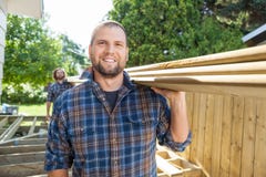 Happy Carpenter And Coworker Carrying Lumbers At Royalty Free Stock Image Happy Carpenter And Coworker Carrying Lumbers At Royalty Free Stock Image
