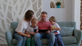 Happy Caucasian family using digital tablet in living room at home stock video footage Happy Caucasian family using digital tablet in living room at home stock video footage