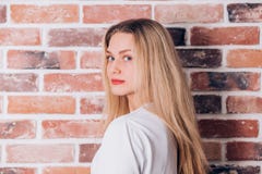 Happy cheerful young lovely blonde woman smiling and looking at the camera near brick wall stock photos Happy cheerful young lovely blonde woman smiling and looking at the camera near brick wall stock photos