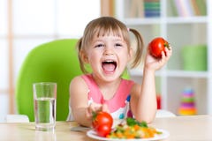 Happy child eats dinner and shows tomatoes royalty free stock photography Happy child eats dinner and shows tomatoes royalty free stock photography