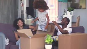 Happy child girl jump out of box play with black parents