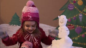 Girl sculpts a snowman in winter. Emotional portrait of cute little girl in winter. background of a painted Christmas stock video Girl sculpts a snowman in winter. Emotional portrait of cute little girl in winter. background of a painted Christmas stock video