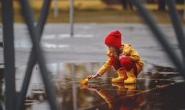 Happy child girl with umbrella and paper boat in puddle in a Stock Images Happy child girl with umbrella and paper boat in puddle in a Stock Images