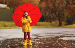 Happy child girl with an umbrella and rubber boots jump in puddl Royalty Free Stock Photo Happy child girl with an umbrella and rubber boots jump in puddl Royalty Free Stock Photo