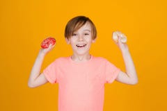 Happy Child Having Fun With Donuts. Tasty Food For Kids. Cute Boy Showing Donuts, Over Yellow Wall Royalty Free Stock Images Happy Child Having Fun With Donuts. Tasty Food For Kids. Cute Boy Showing Donuts, Over Yellow Wall Royalty Free Stock Images