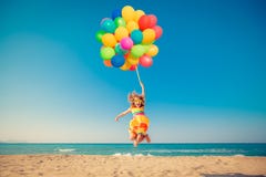 Happy child jumping with colorful balloons on sandy beach stock photos Happy child jumping with colorful balloons on sandy beach stock photos