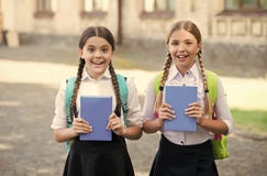Happy children in school uniforms hold study books outdoors, knowledge