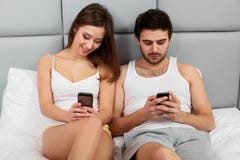Happy Couple in a Bed with Mobile Phones royalty free stock photography Happy Couple in a Bed with Mobile Phones royalty free stock photography
