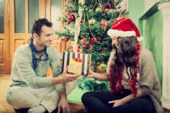 Happy couple exchanging gifts at home by Christmas tree royalty free stock photography Happy couple exchanging gifts at home by Christmas tree royalty free stock photography